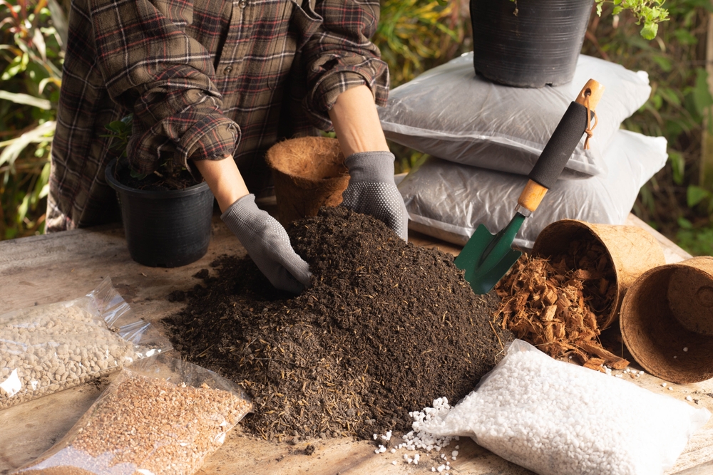 Gardening concept. A young woman mixes potting soil, prepares the soil for planting vegetables and herbs in the house, mixes potting soil, perlite, vermiculite, peat, worm, coconut flakes, rice husk.